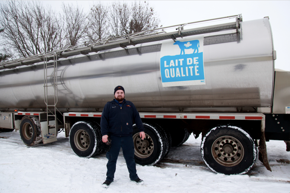 Un chauffeur de camion de lait devant son camion 