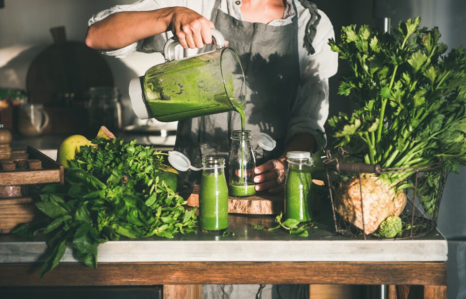 Femme versant des smoothies verts dans des pots de vitre.